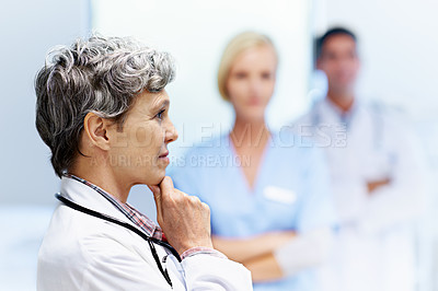 Buy stock photo Profile shot of a mature doctor with colleagues in the background