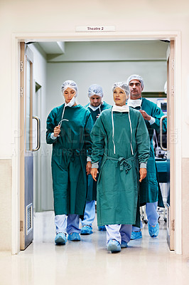 Buy stock photo Shot of a team of surgeons walking out of an operating room