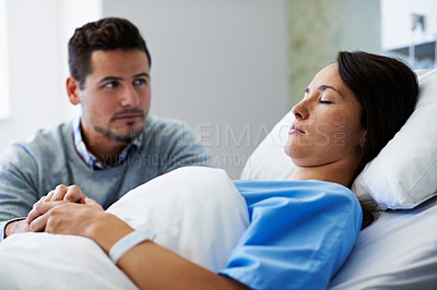 Buy stock photo Shot of a woman lying in a hospital bed being comforted by her husband