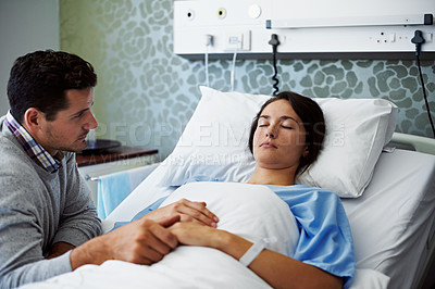 Buy stock photo Shot of a woman lying in a hospital bed being comforted by her husband