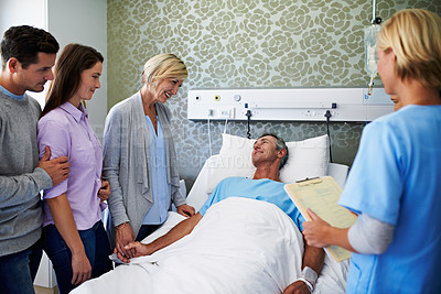 Buy stock photo Shot of a mature man lying in a hospital bed with his family next to him