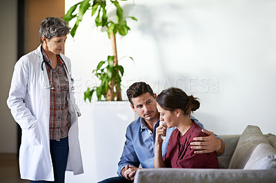 Buy stock photo Shot of a doctor talking to a grieving woman and her husband in a hospital waiting room
