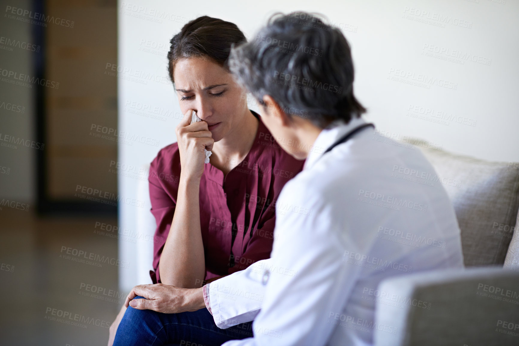 Buy stock photo Shot of a compassionate doctor comforting a young woman in a hospital waiting room