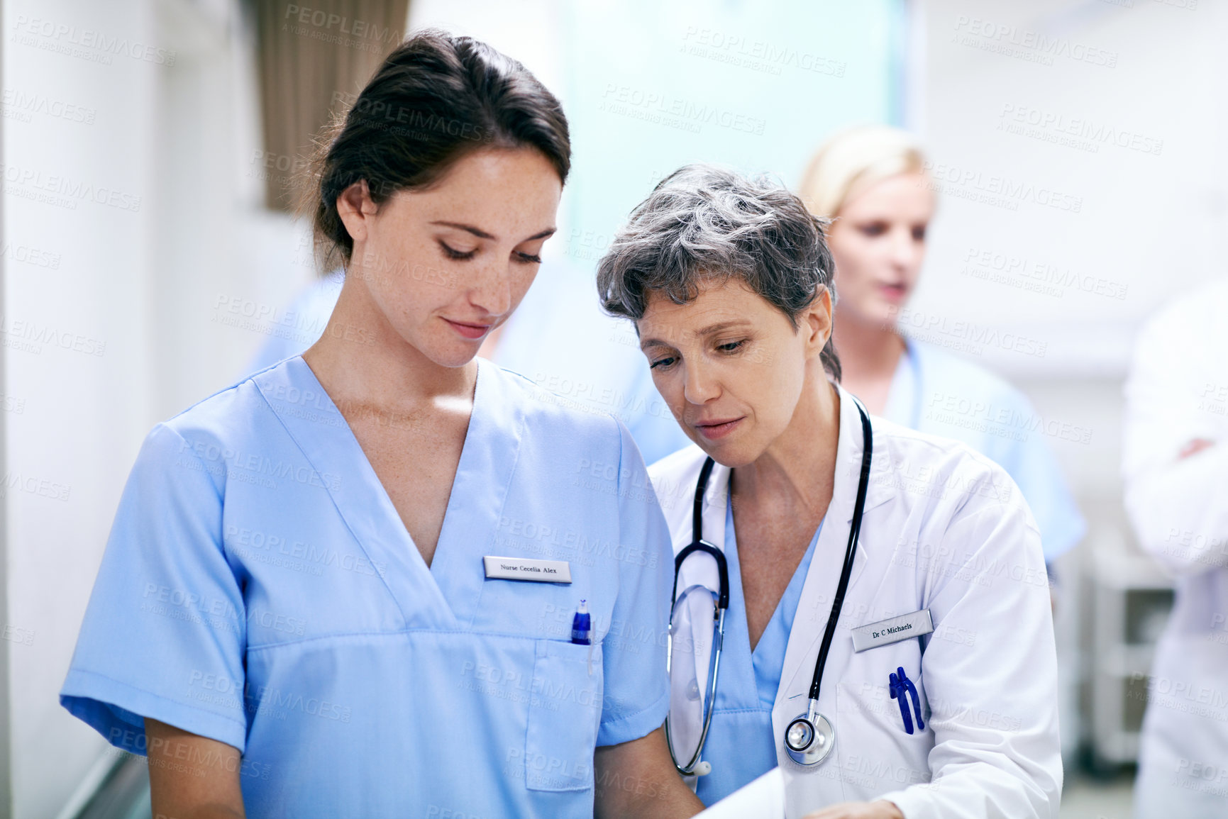 Buy stock photo Shot of a group of medical professionals walking down a hospital corridor