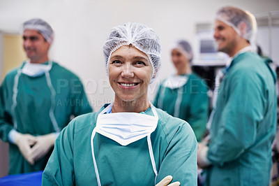 Buy stock photo Portrait of a confident doctor in the operating room with her surgical team in the background