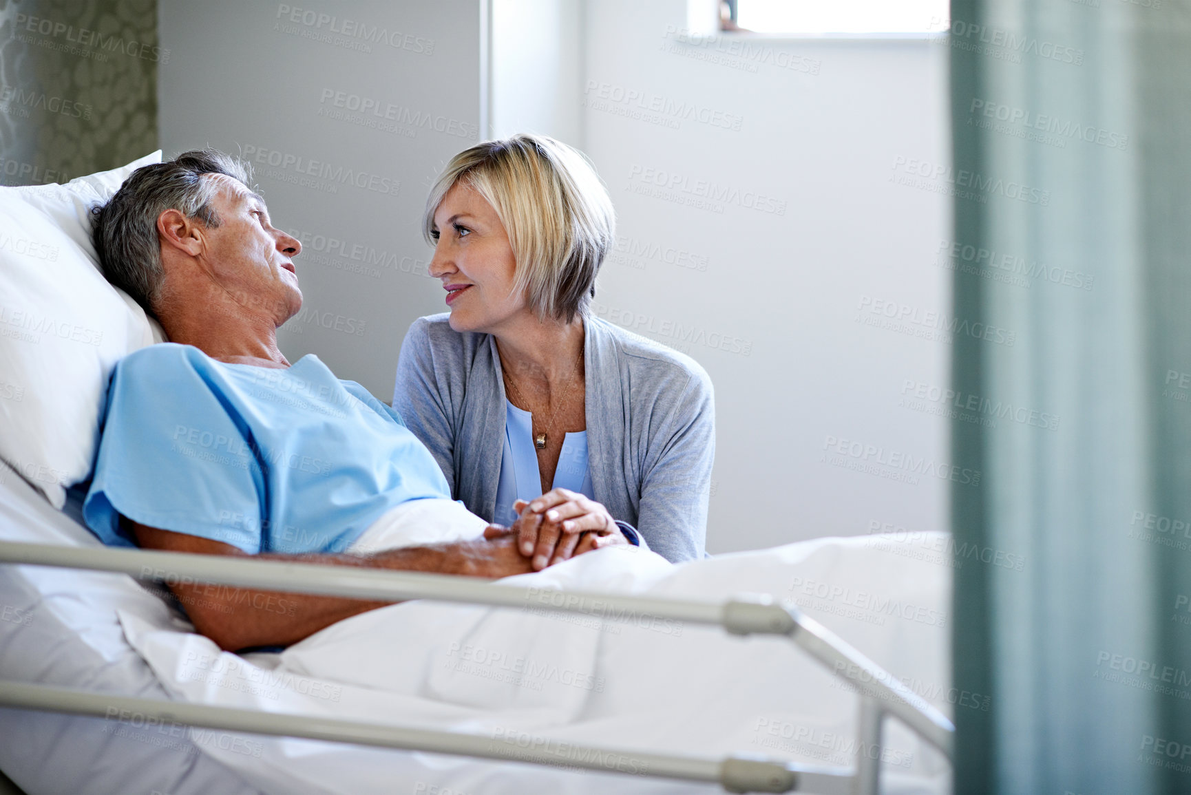 Buy stock photo Shot of a woman comforting her husband lying in a hospital bed