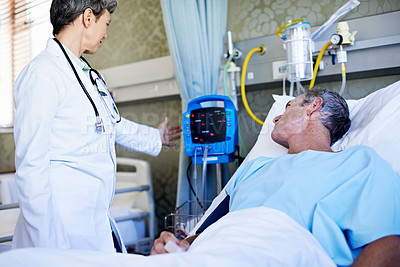 Buy stock photo Shot of a doctor examining a patient's vitals in a hospital ward