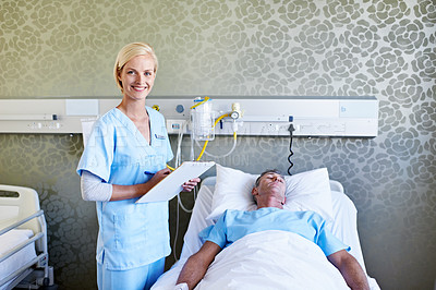 Buy stock photo Shot of a nurse reading a medical chart beside a patient in a hospital bed