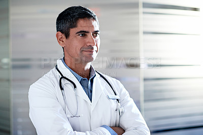 Buy stock photo Shot of a mature male doctor standing in a hospital corridor