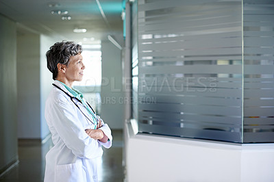 Buy stock photo Shot of a mature female doctor standing in a hospital corridor