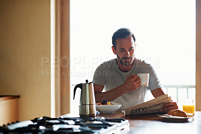 Buy stock photo Shot of a man reading the newspaper while having breakfast