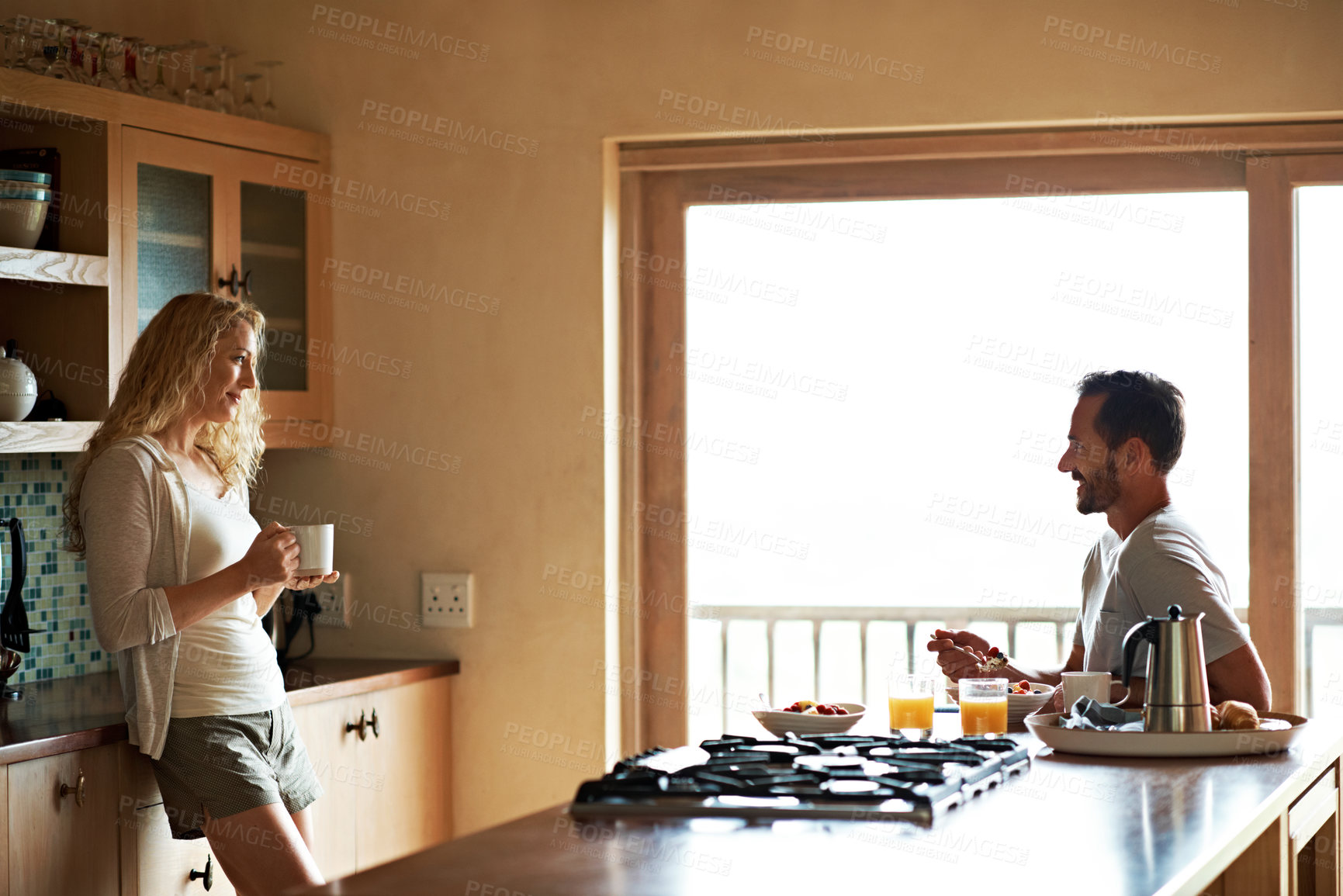 Buy stock photo Shot of a man and his wife having breakfast in their kitchen