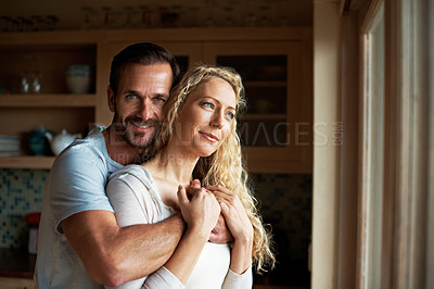 Buy stock photo Portrait shot of a man embracing his wife while she stares out the window