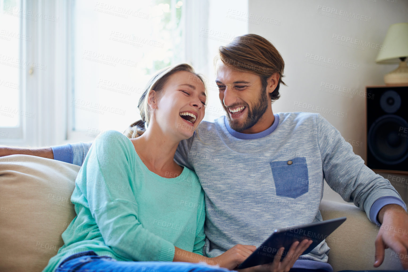 Buy stock photo Shot of a young couple using a digital tablet while relaxing on a sofa at home