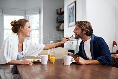 Buy stock photo Shot of a loving young couple eating breakfast at their dining table