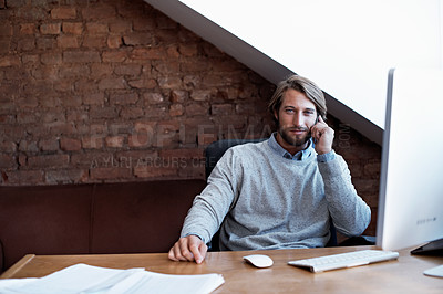 Buy stock photo Portrait of a young man talking on the phone while working on a computer at home