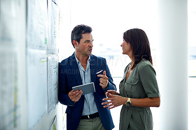 Buy stock photo Shot of two colleagues talking together in an office hallway
