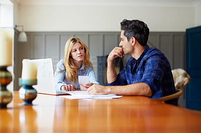 Buy stock photo Shot of a young couple sitting together at their kitchen table paying bills online