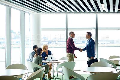 Buy stock photo Shot of a two colleagues shaking hands during a meeting