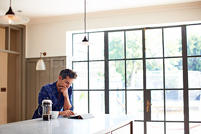 Buy stock photo Shot of a young man having breakfast and using a digital tablet in his kitchen