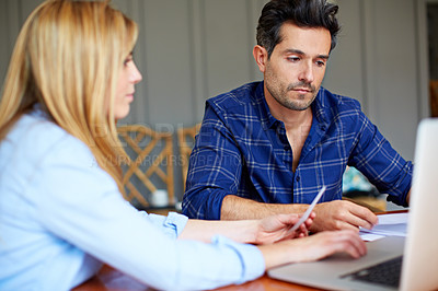 Buy stock photo Shot of a young couple sitting together at their kitchen table paying bills online