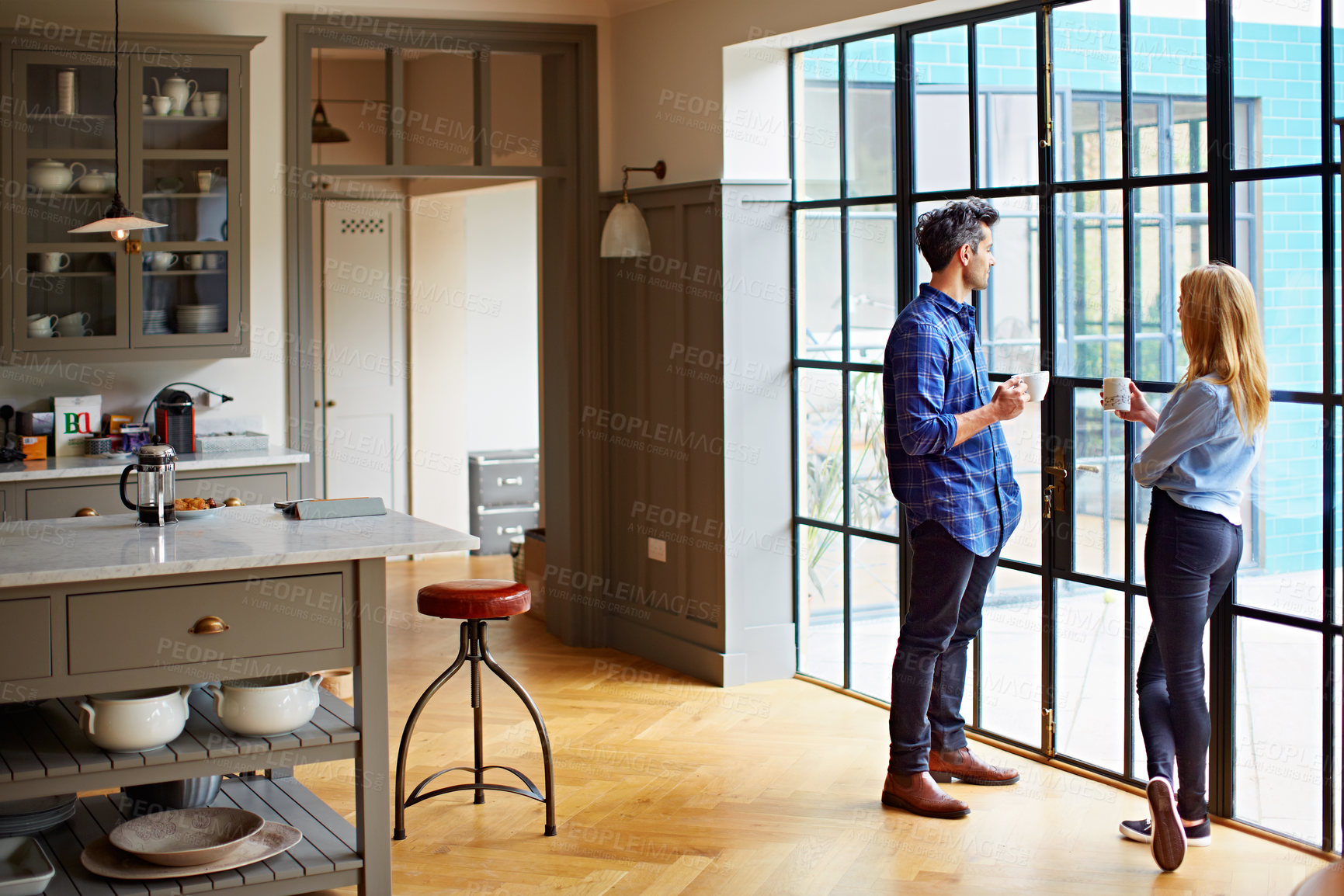Buy stock photo Shot of a young couple drinking coffee together in their kitchen