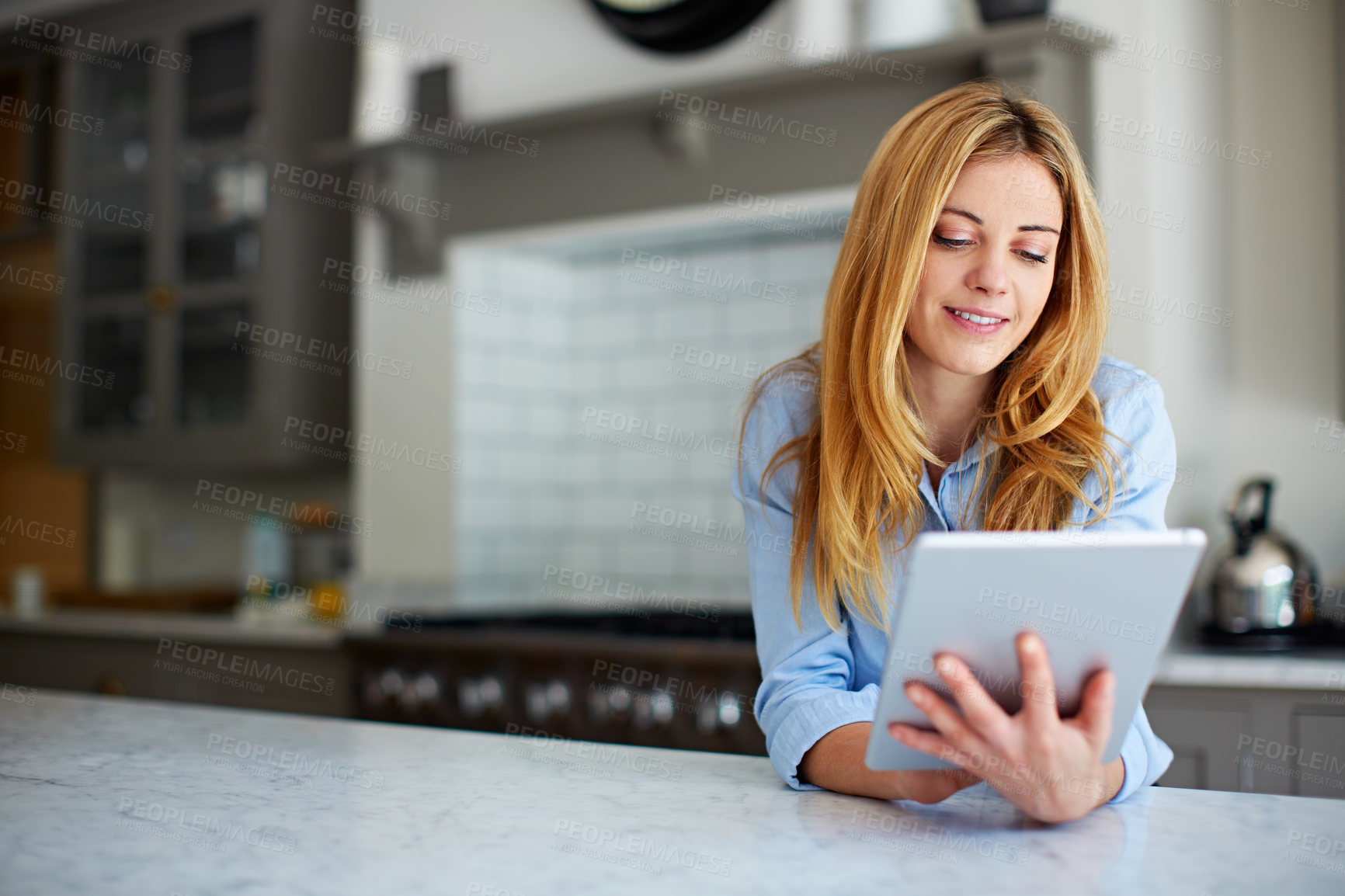 Buy stock photo Woman, relax and reading at house with tablet, social media and browsing online for latest movies. Smile, person and rest in kitchen with digital app, internet search and streaming for film watchlist