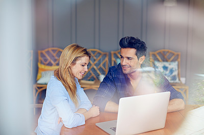 Buy stock photo Shot of a young couple sitting together at their kitchen table using a laptop