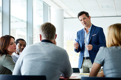 Buy stock photo Shot of a man giving a presentation to coworkers in an office