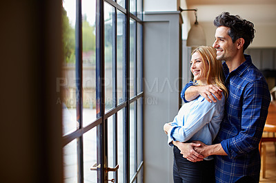 Buy stock photo Shot of a smiling young couple hugging each other in their kitchen