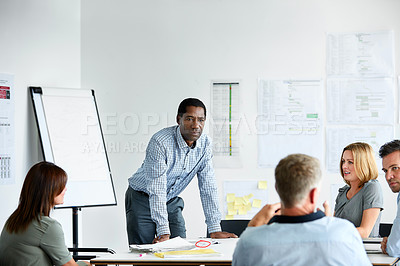 Buy stock photo Shot of a man giving a presentation to a group of colleagues sitting together in a modern office