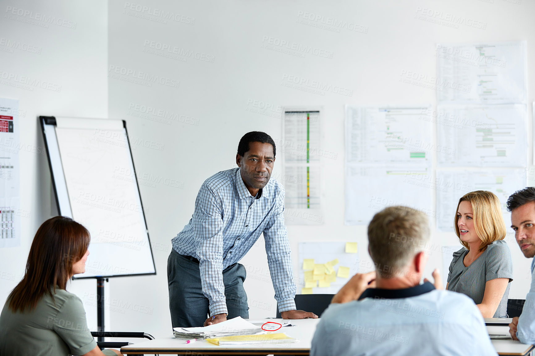 Buy stock photo Shot of a man giving a presentation to a group of colleagues sitting together in a modern office
