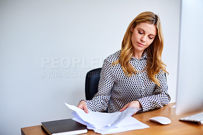 Buy stock photo Shot of a young woman sorting paperwork while sitting at a desk in her home office