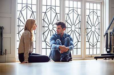 Buy stock photo Shot of a young couple talking together while sitting on their living room floor