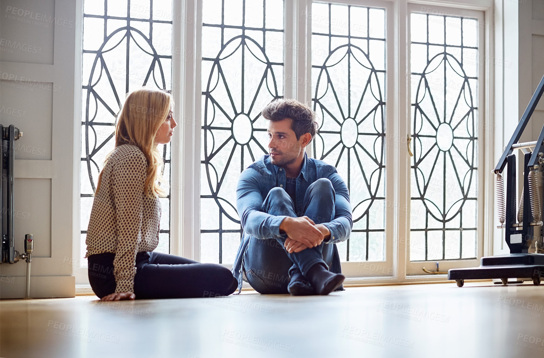 Buy stock photo Shot of a young couple talking together while sitting on their living room floor