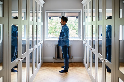Buy stock photo Shot of a man getting dressed in a long walk in closet full of mirrors
