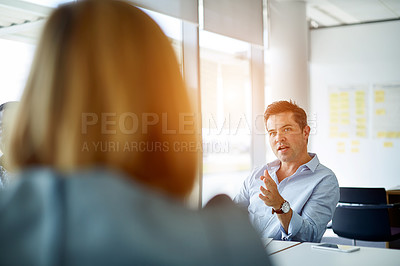 Buy stock photo Shot of two coworkers talking together while sitting in an office