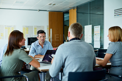 Buy stock photo Shot of colleagues having a meeting around a boardroom table in an office