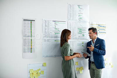 Buy stock photo Shot of two colleagues talking together in an office hallway