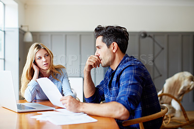 Buy stock photo Shot of a young couple sitting together at their kitchen table paying bills online