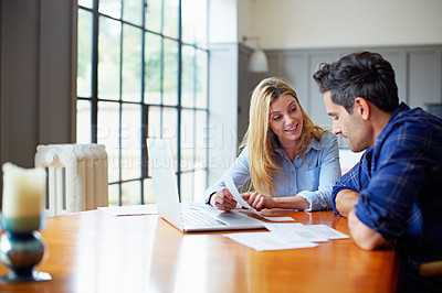 Buy stock photo Shot of a young couple sitting together at their kitchen table paying bills online