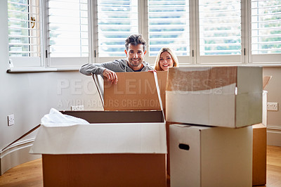 Buy stock photo Portrait of a smiling couple sitting in a large box while moving into a new home