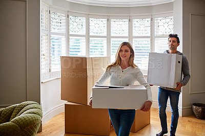 Buy stock photo Shot of a happy young couple carrying boxes in their new house
