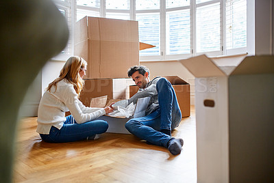 Buy stock photo Shot of a happy young couple unpacking boxes in their new house