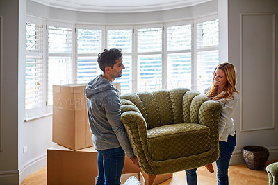 Buy stock photo Shot of a happy young couple carrying a chair in their new house
