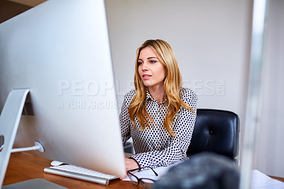 Buy stock photo Shot of a young woman working on a computer while sitting at a desk in her home office