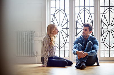 Buy stock photo Shot of a young couple talking together while sitting on their living room floor