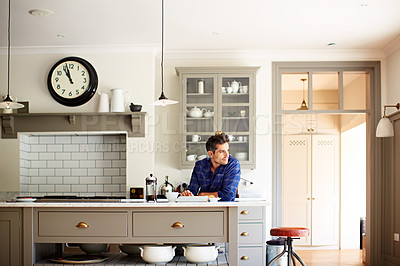 Buy stock photo Shot of a young man having breakfast and using a digital tablet in his kitchen