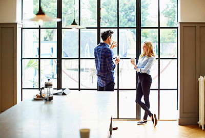 Buy stock photo Shot of a young couple drinking coffee together by a window in their kitchen
