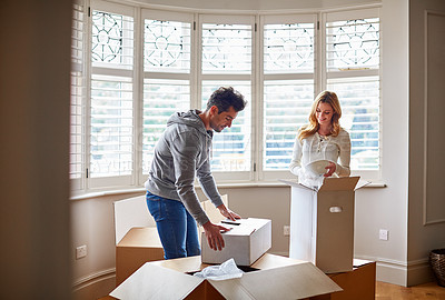 Buy stock photo Shot of a happy young couple unpacking boxes in their new house
